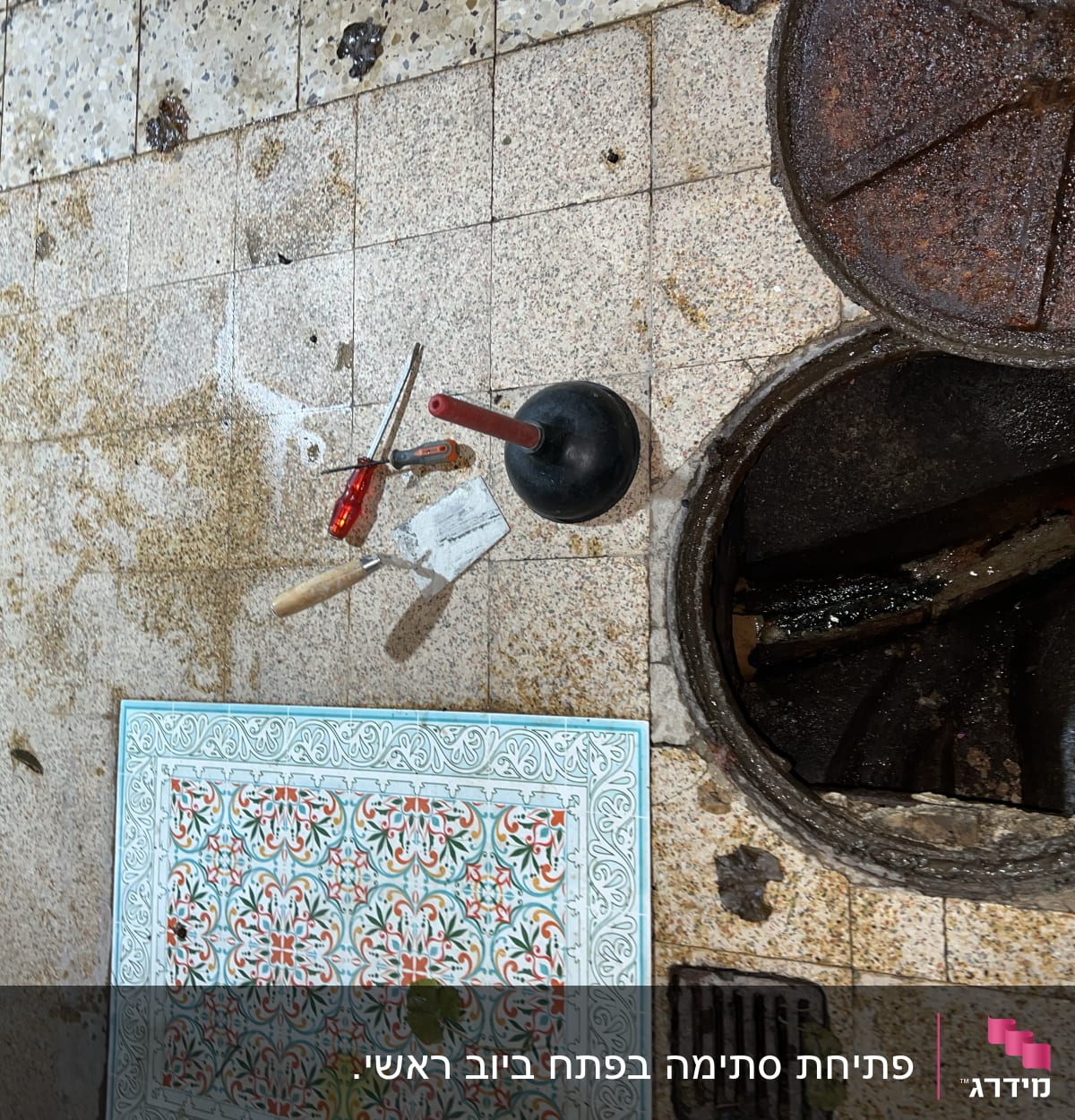 כלי עבודה של אינסטלטור ליד פתח ביוב פתוח